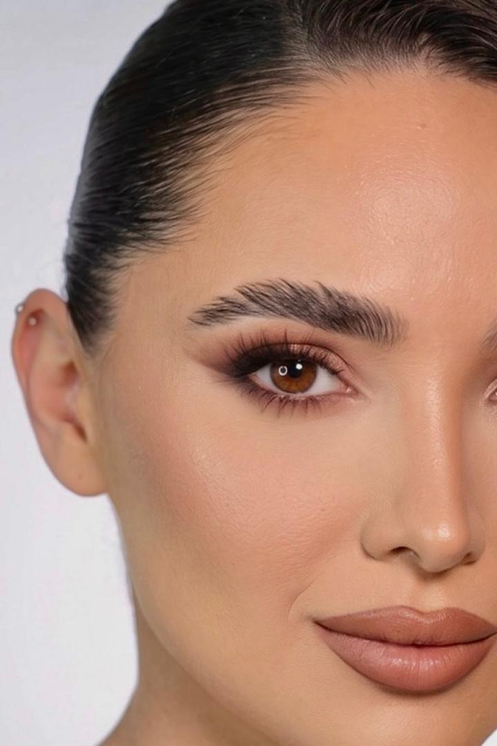 Primer plano de maquillaje editorial con piel luminosa, ojos definidos y labios de tono neutro