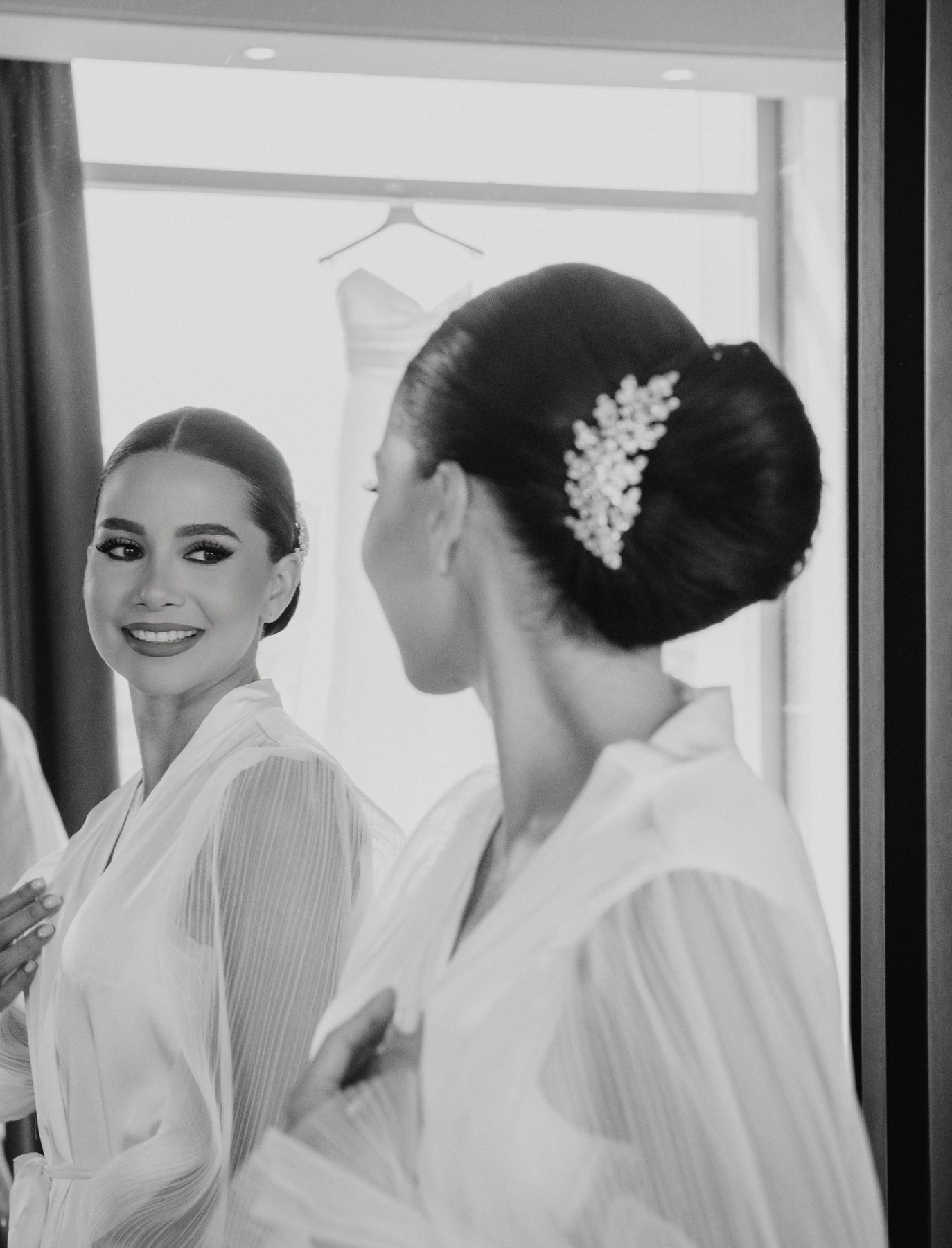 Fotografía en blanco y negro de una novia frente al espejo, con un recogido y un accesorio en el cabello
